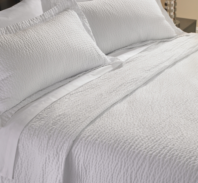 White bed with Pillows and a rippled coverlet